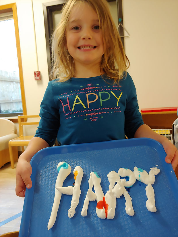 Montessori child with HAPPY shirt and art