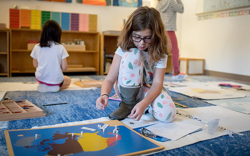 girl in Montessori School working with a map